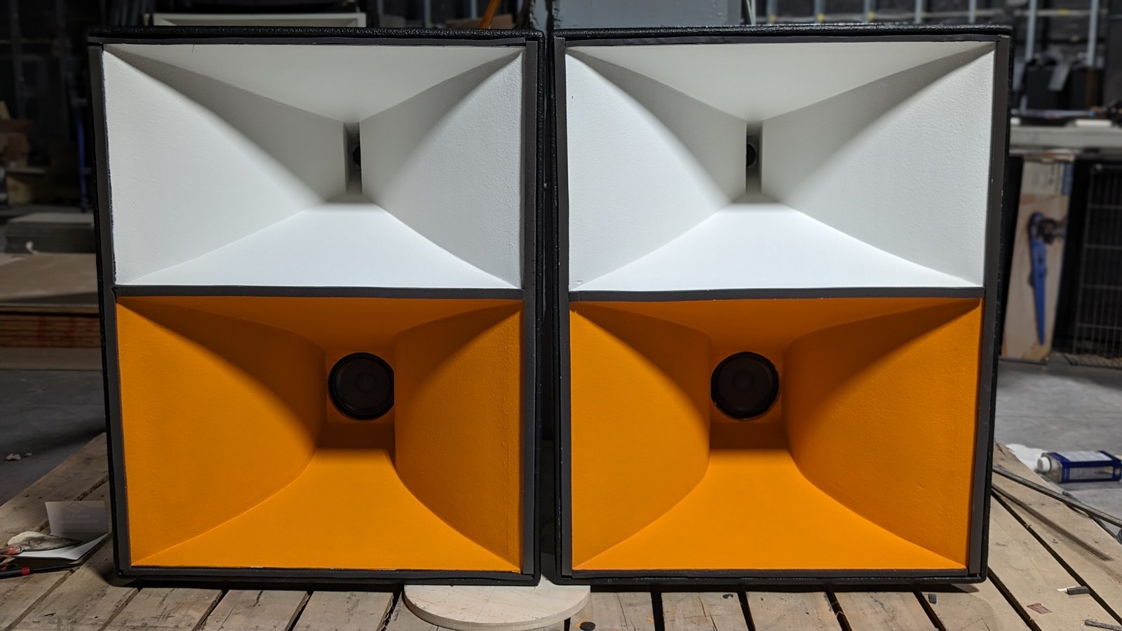 A pair of Sound Logic orange and white horn speaker cabinets in the workshop